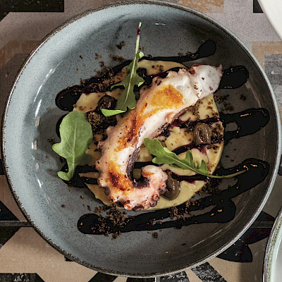 Gebakken octopustentakels met Taggiasche olijven, crème van kikkererwten en coulis van blauwe bessen